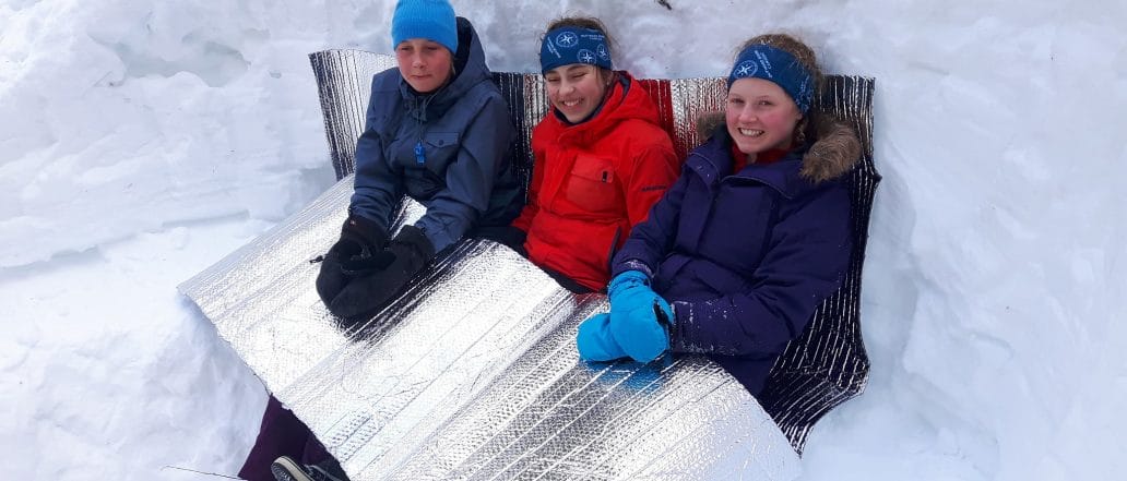 group of girls smiling sitting in the snow