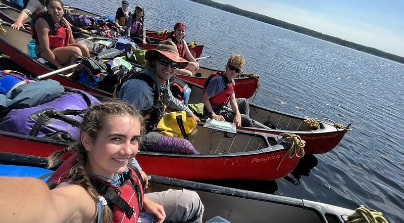 teens smiling in canoes on a lake