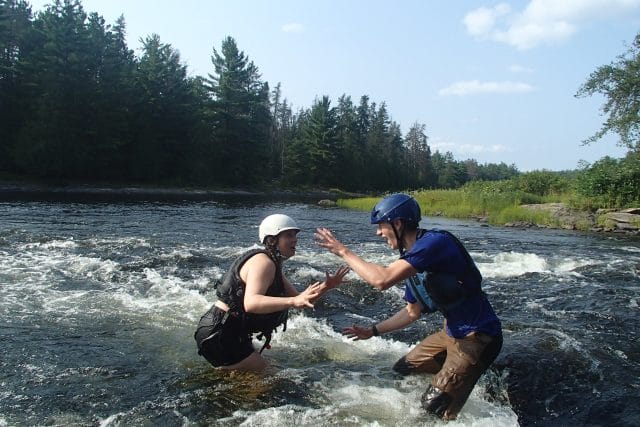 two teens making silly faces at eachother standing in white water