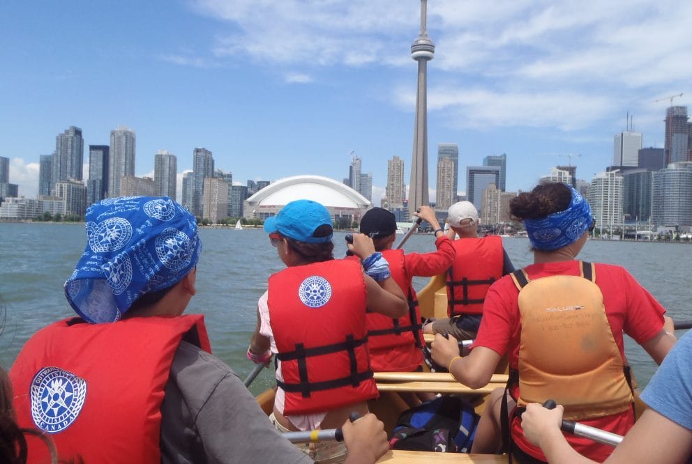 teens canoeing with toronto skyline in the forefront