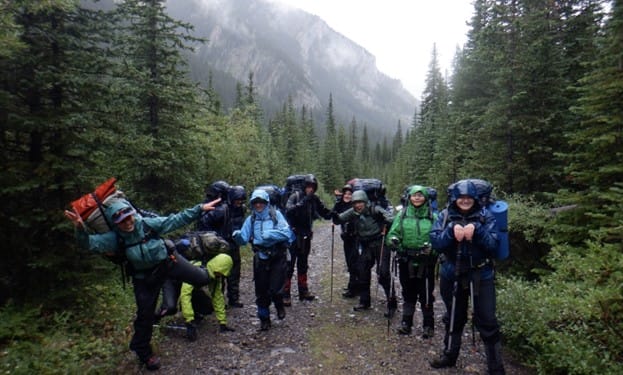 Participants of Maya Carr's OBC expedition carrying backpacks on a trail in the Canadian Rocky Mountains