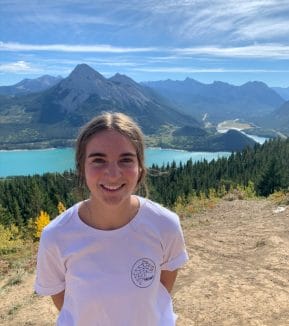 Maya Carr smiling near a lake in the Canadian Rocky Mountains