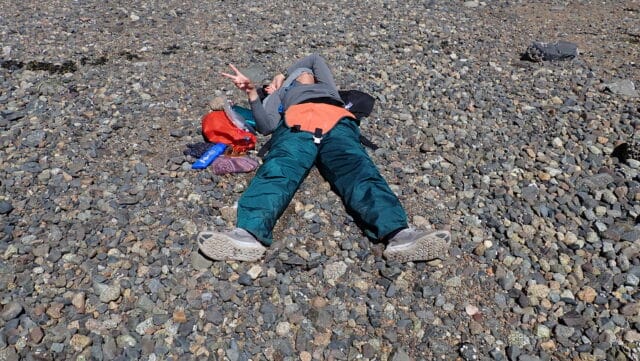 teen lying on the ground throwing up peace sign