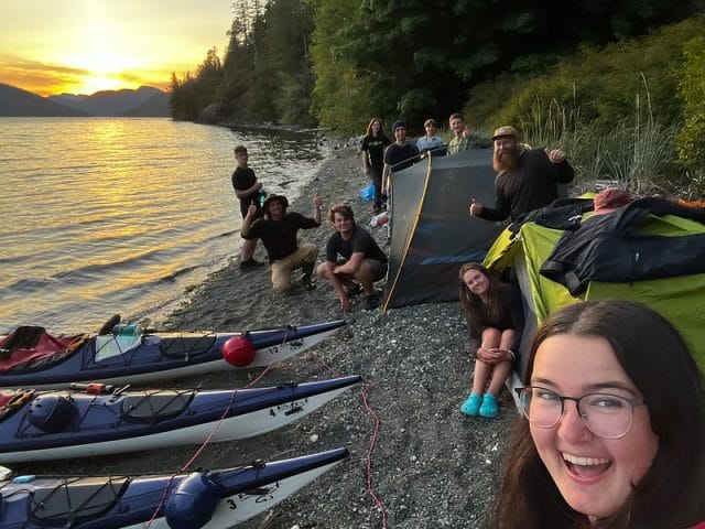 teens taking a selfie infront of sea sunset and kayaks