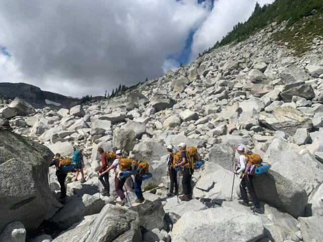 teens hiking rocks in backpacking gear