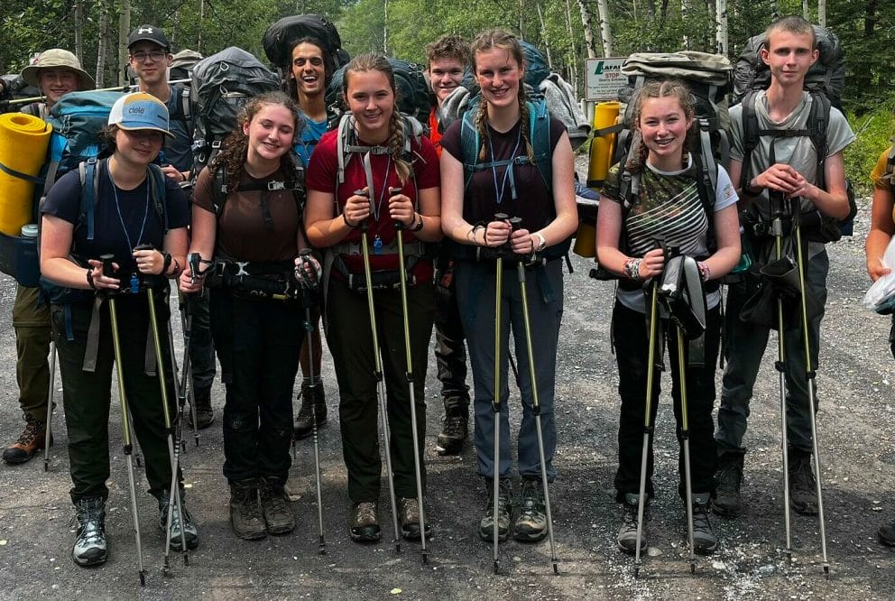teens in hiking gear smiling on a trail