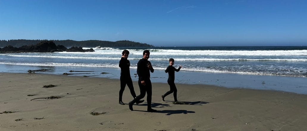 boys smiling in wet suits on a beach