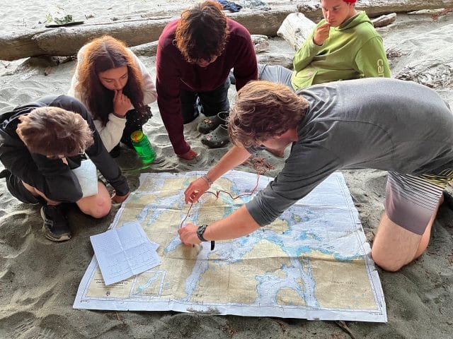 teens studying a map on a beach