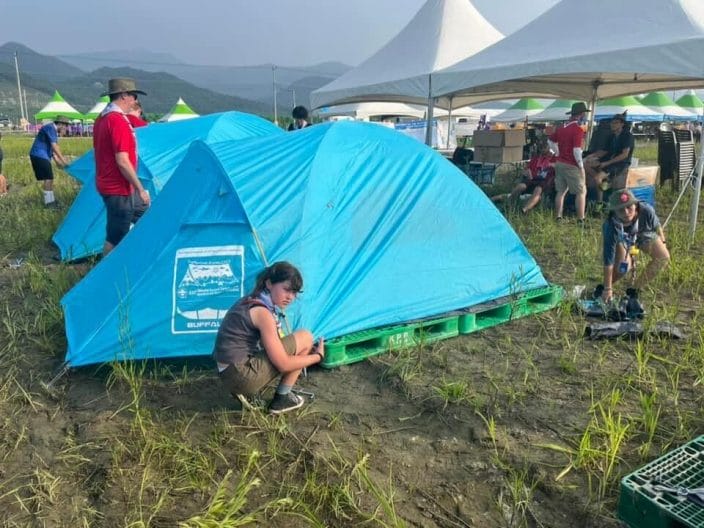 Two Scouts pitch a camping tent on plastic pallets at the 25th World Jamboree in South Korea