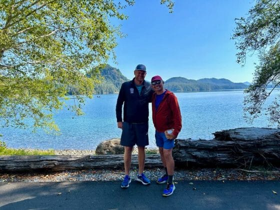 two men standing with lake and mountains behind