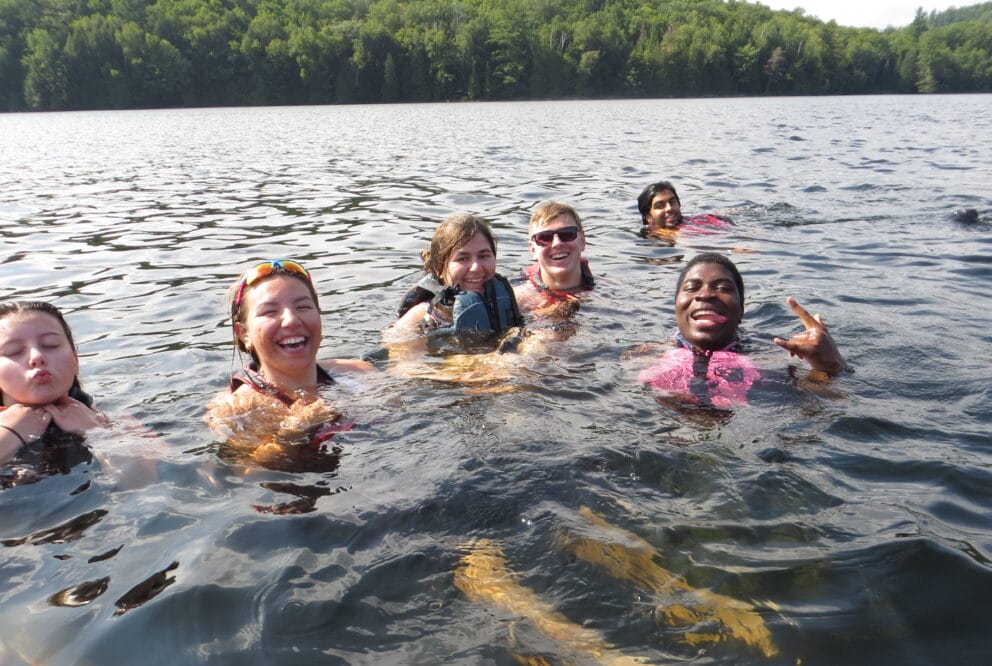 Group of five youth swimming in a lake in Algonquin Park