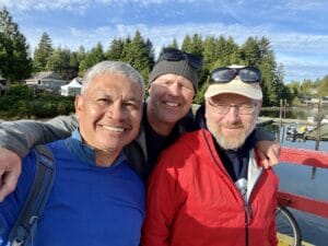 three men in hats smiling with lake and trees in background