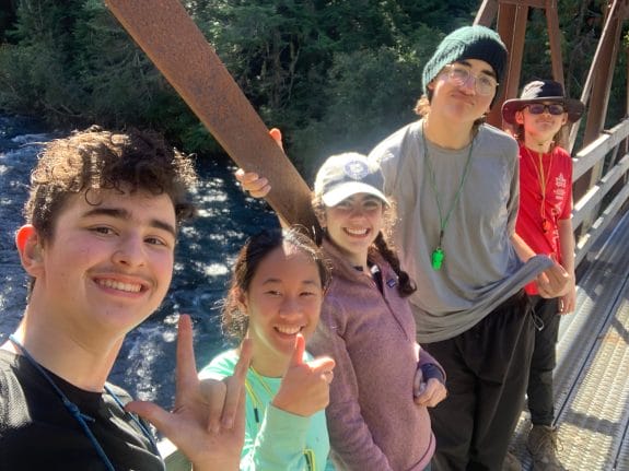teens smiling and posing for a selfie on a bridge