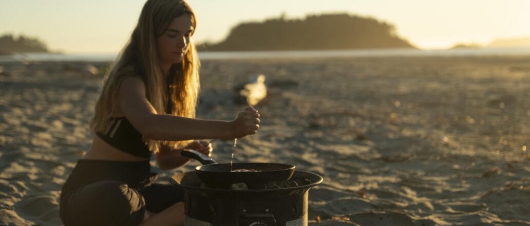 Image of a teen cooking on a campstove on a beach