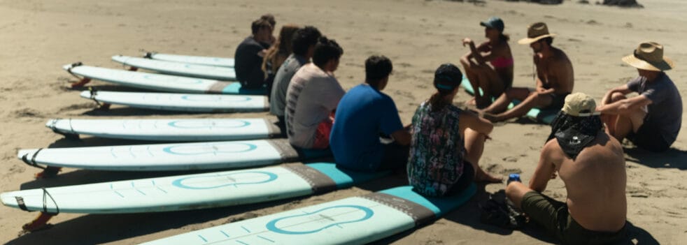 Group of teens sitting on surfboards in a semi circle