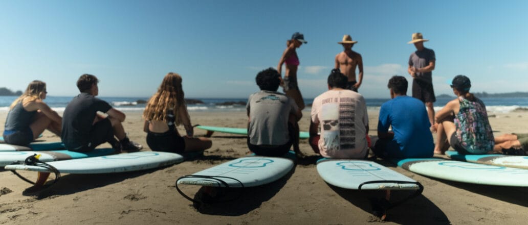 Group of teens sitting on surfboards in a semi circle