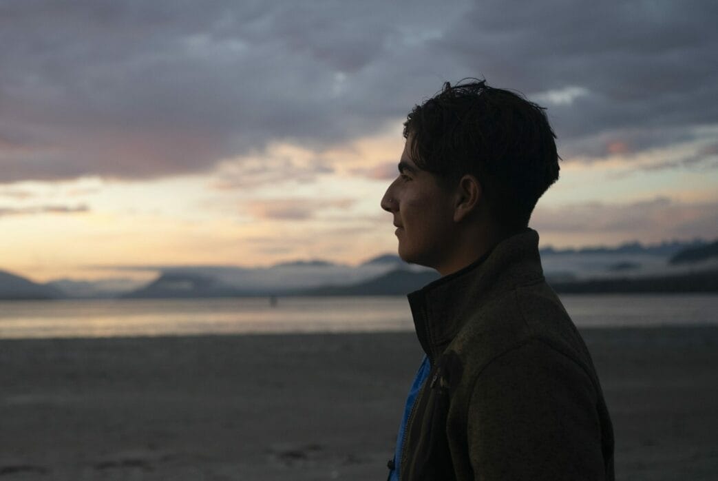 A teen looking out at the ocean at sunset