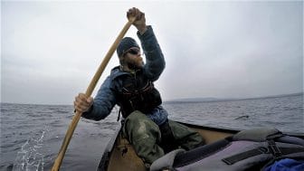 man paddling a canoe on a lake